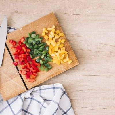 fresh-organic-chopped-red-yellow-green-bell-peppers-chopping-board-with-knife-wooden-desk-rid